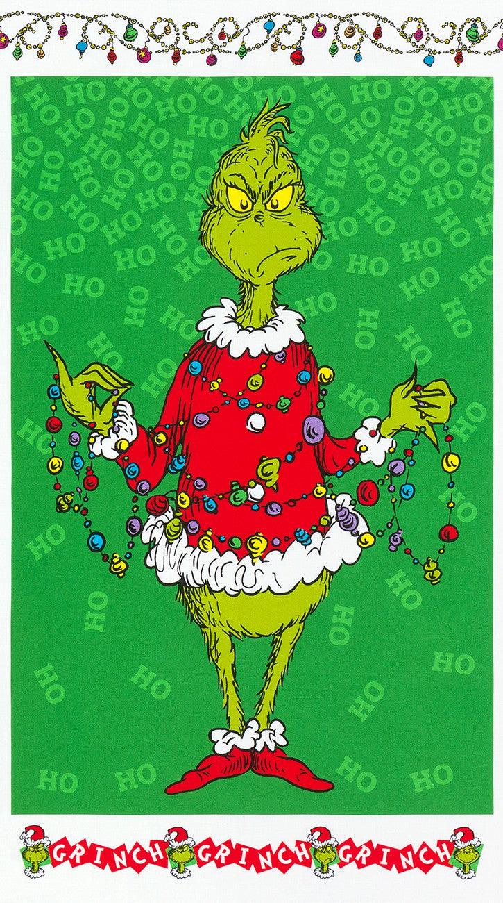 The Grinch in a red Santa coat holding strings of holiday lights and ornaments